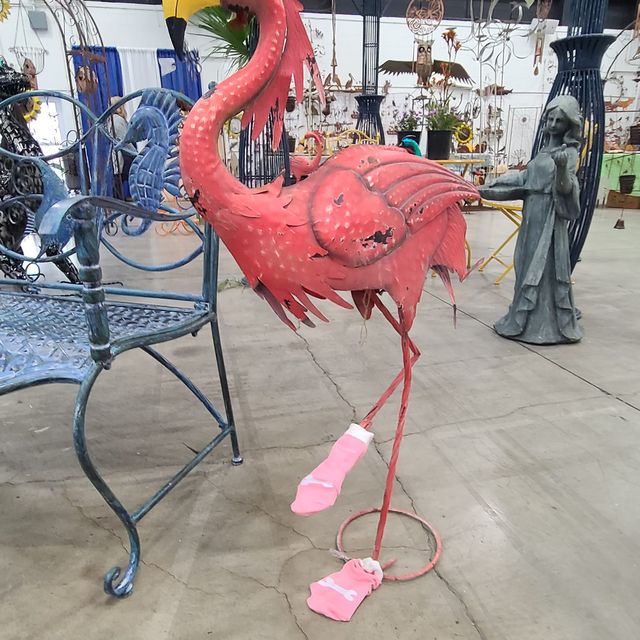 A metal pink flamingo sculpture in pink socks
