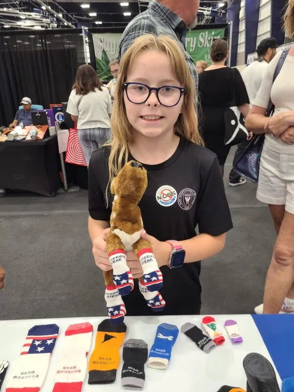 A girl holding a stuffed miniature horse wearing socks